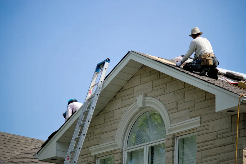 Roofers inspecting the rake edge of a gabled stone home