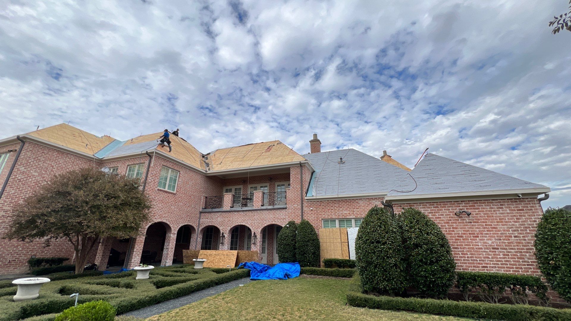 Roofing crew working on a large brick home
