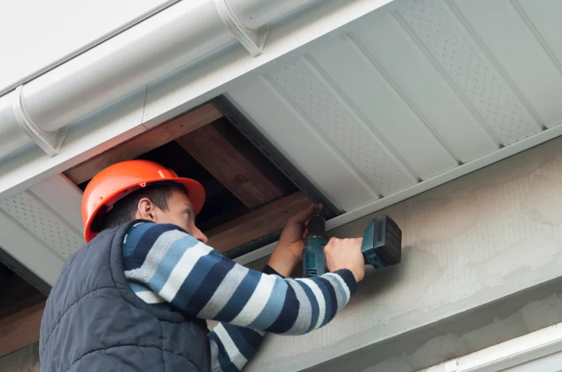 Technician installing soffit ventilation under a roof eave