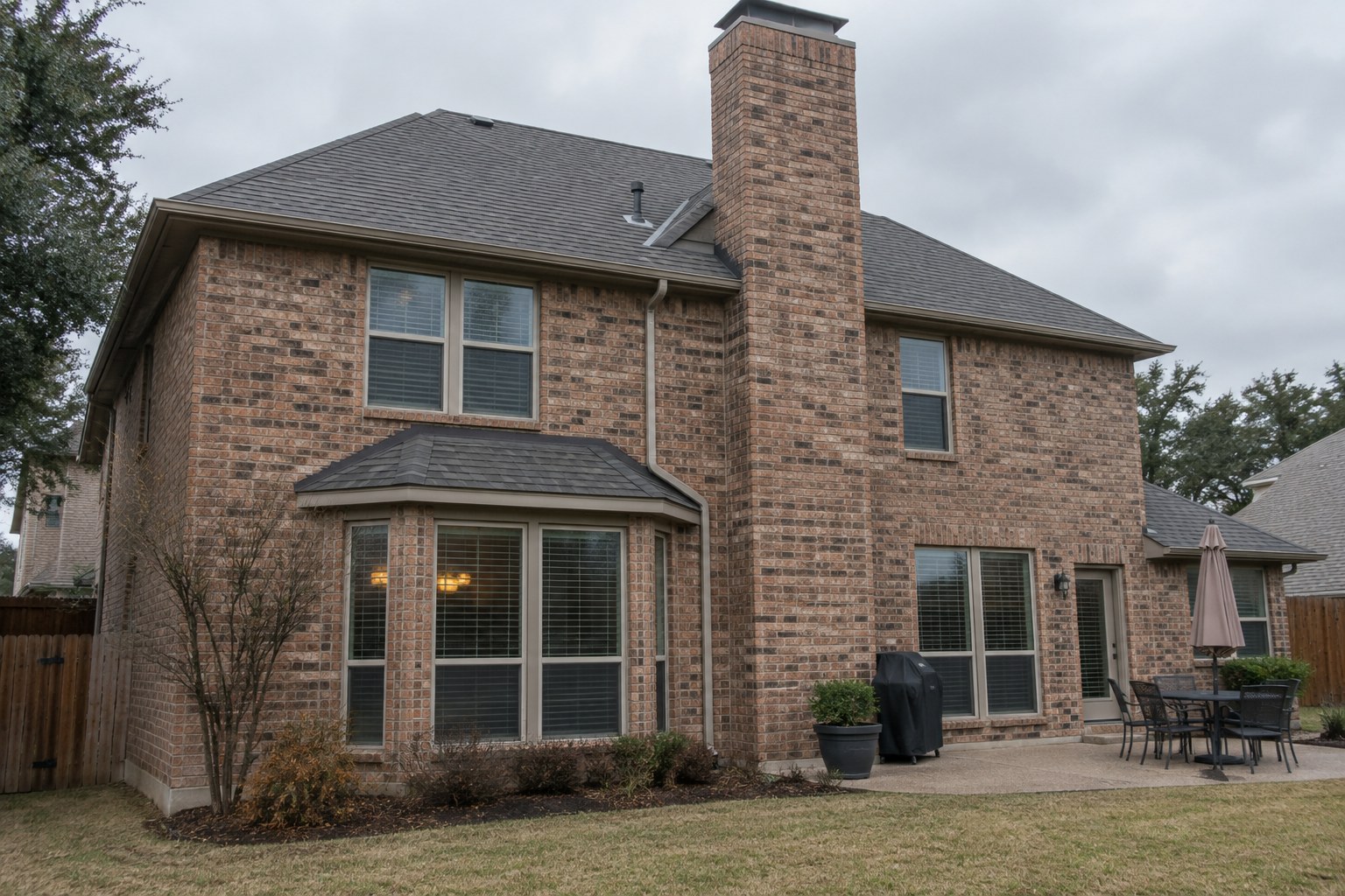 Brick chimney on a North Texas shingle roof with a small cricket built behind it