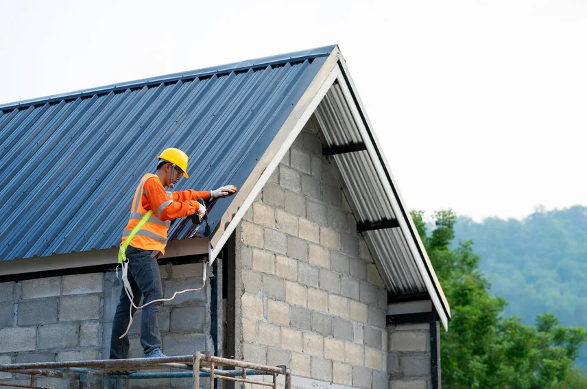 Roofer installing rake trim on a metal roof