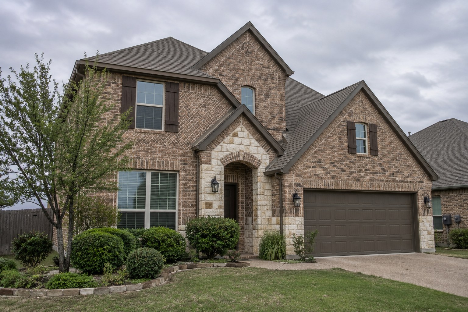 Brick two story Allen home with shingle roof valleys where front gables meet the main roof