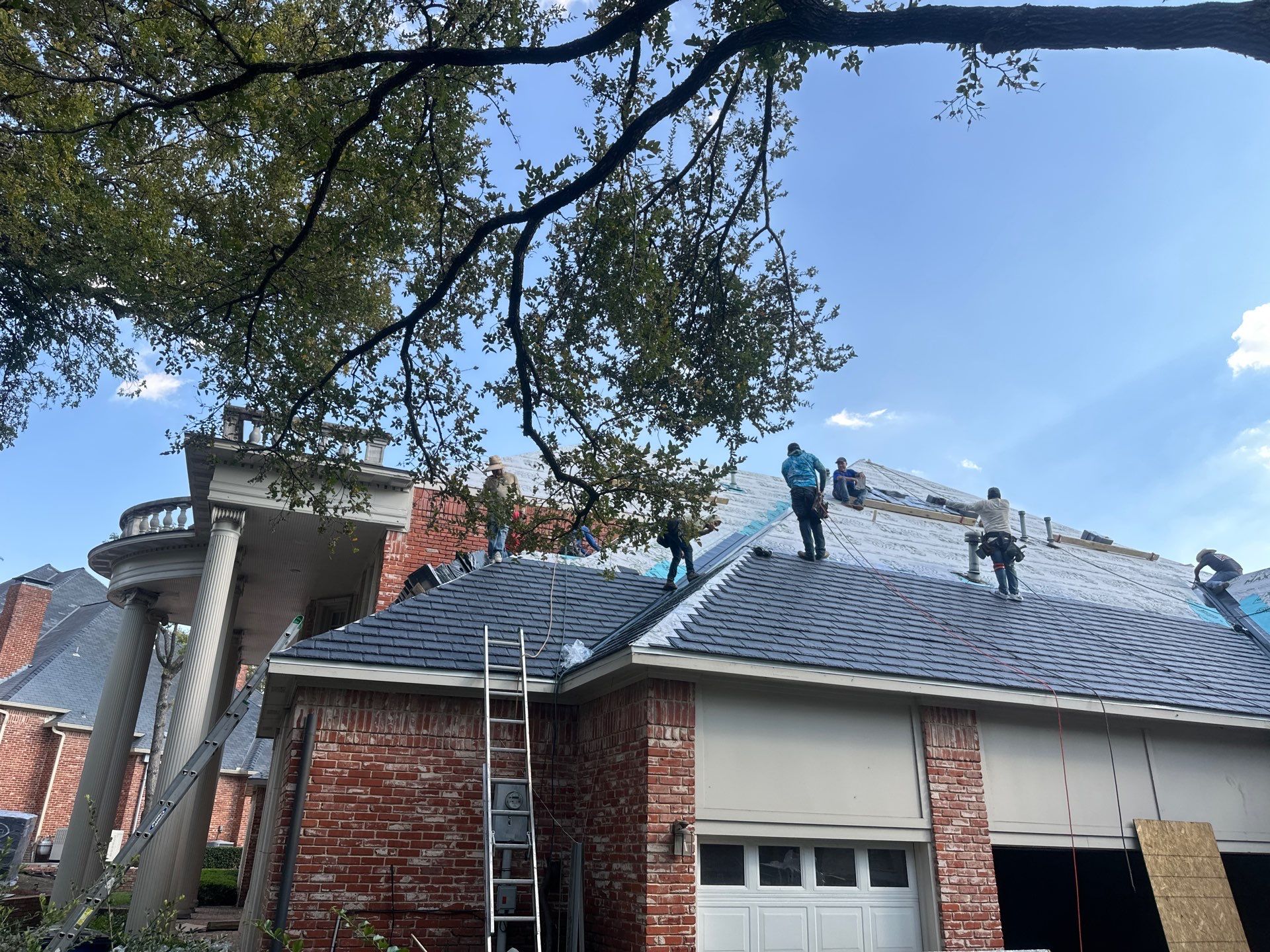 Roofing crew replacing a shingle roof on a brick home