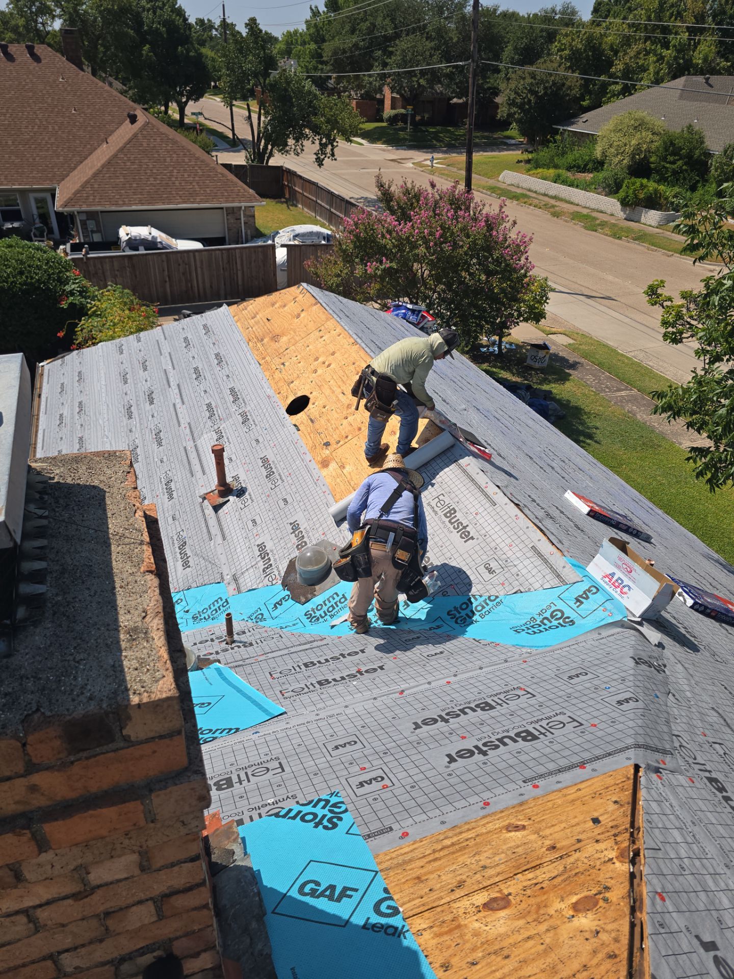 Roofing crew installing shingles on a brick home