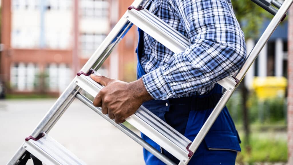 a roofing contractor holding a ladder