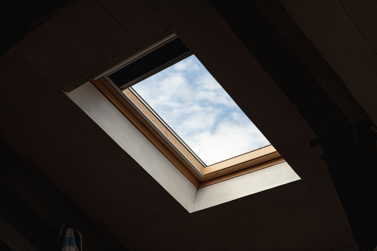 a ceiling window allowing one to see droplets of rain on the roof